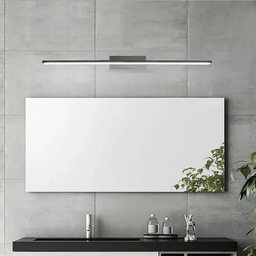 Lustre bar long LED mural fixé au mur gris au-dessus d’un comptoir noir; miroir blanc et plante à droite. Lustre bar long LED mural fixé au mur gris au-dessus d’un comptoir noir; miroir blanc et plante à droite.