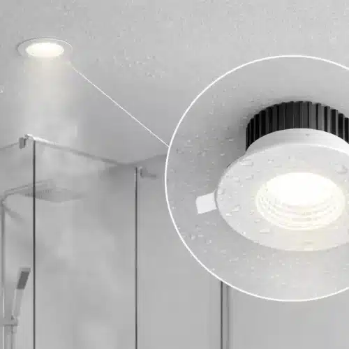 Spot LED encastrable moderne avec dissipateur noir, installé au plafond d’une salle de bains/ douche, zone humide avec éclaboussures d’eau.