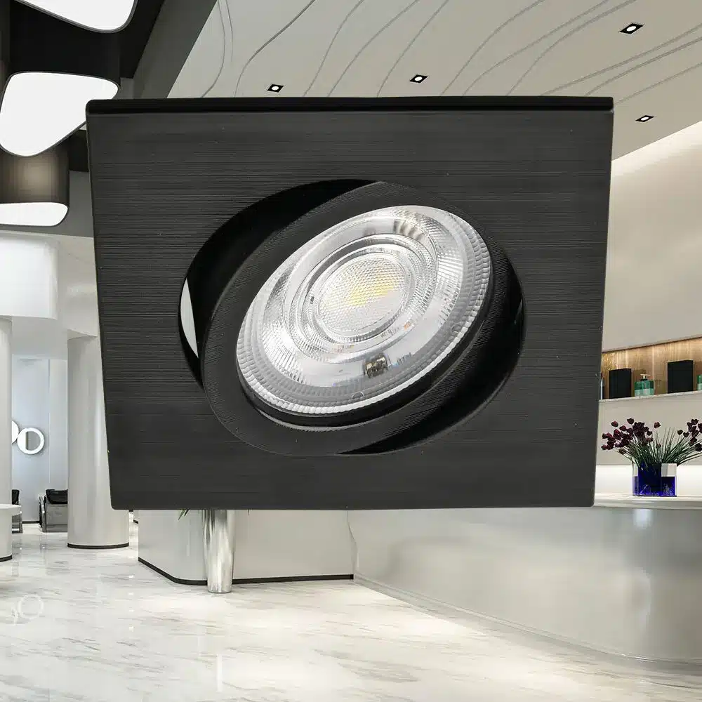 Projecteur LED rond encastré dans un cadre noir carré, luminaire élégant en milieu moderne.