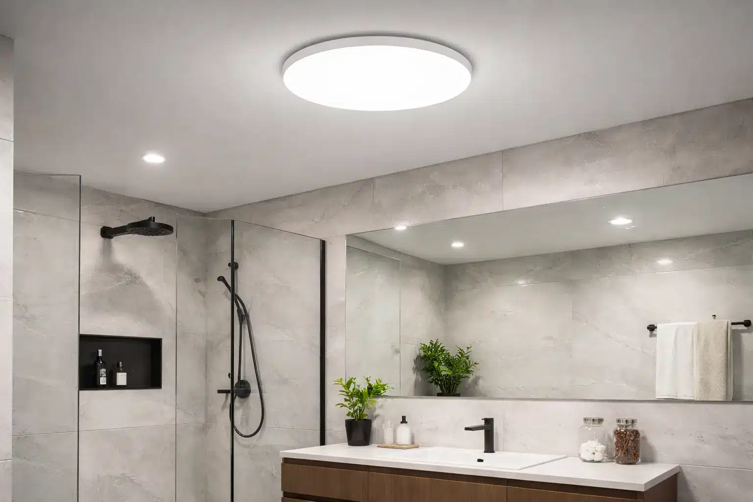 Salle de bains moderne avec douche à l’italienne, grand miroir et meuble lavabo en bois; éclairage LED, plantes et accessoires décoratifs.