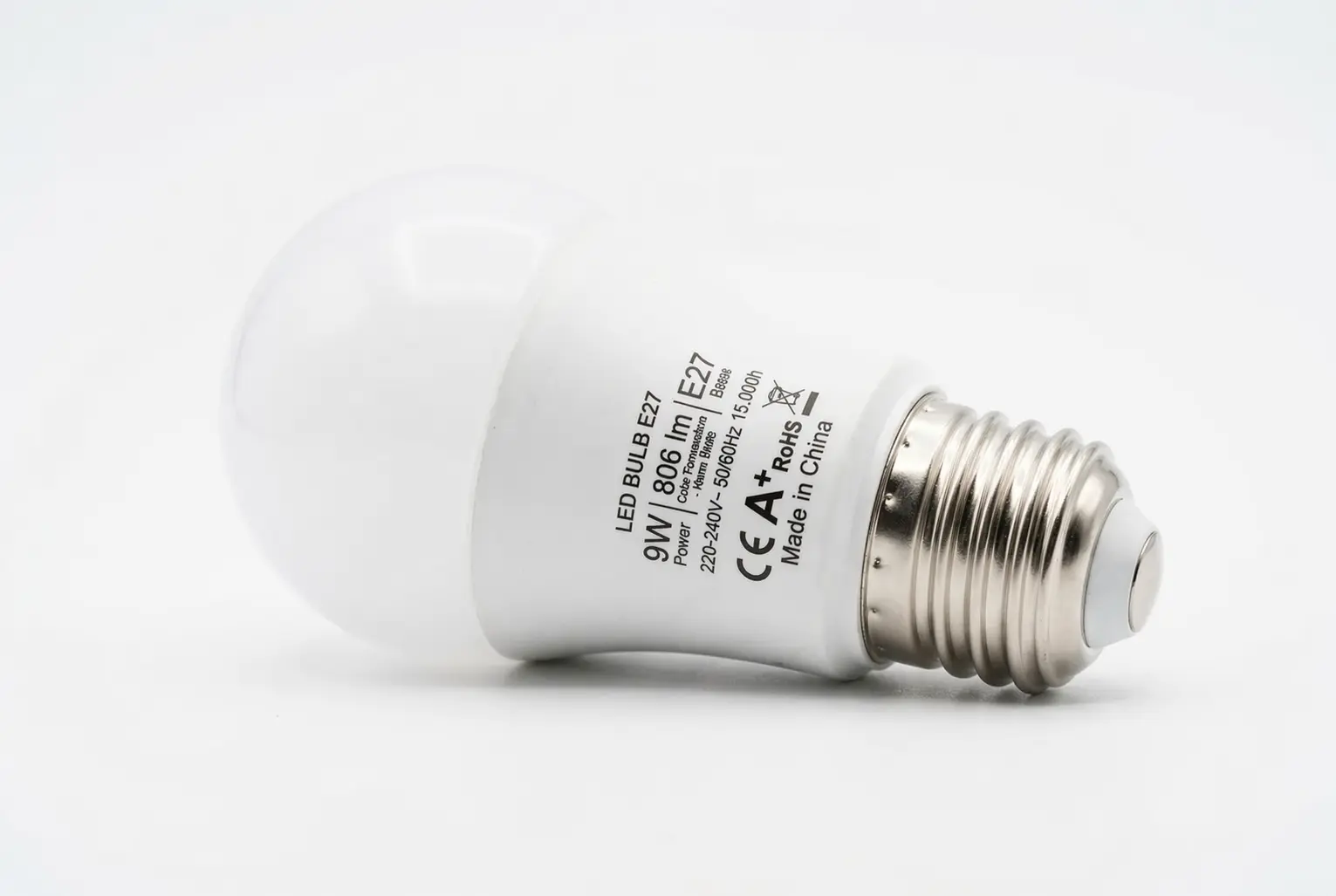 Ampoule LED E27 blanche, refroidie et inclinée sur fond blanc, inscription et norme CE/EA visibles sur le corps métallique.