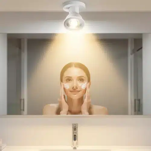 Ampoule LED GU10 encastrée au plafond d'une salle de bain, éclairant doucement le visage d'une femme lors de sa routine de soin de la peau.