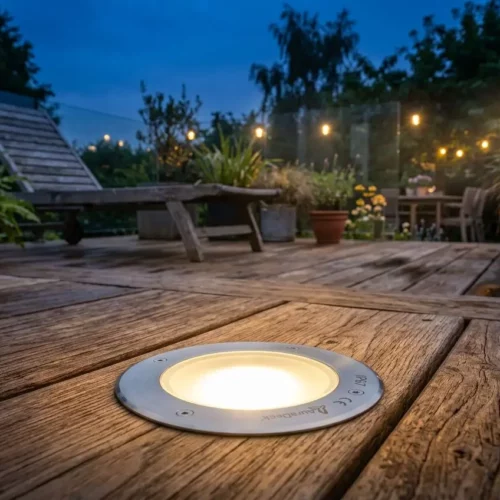 Spot encastré étanche installé dans une terrasse en bois, illuminant un jardin au crépuscule.